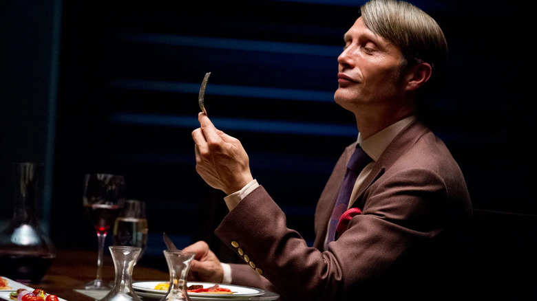 Mads Mikkelsen as Hannibal Lecter, looking at a fork on Hannibal.