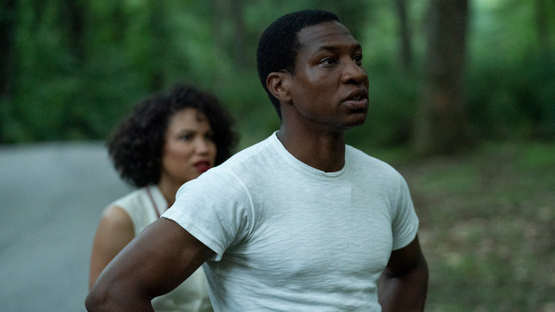 Jonathan Majors as Atticus Freeman and Jurnee Smollett as Leti Lewis, standing on wooded road in Lovecraft Country.