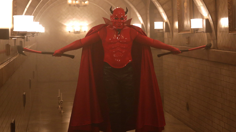 The Red Devil walks down a hall with twin axes in Scream Queens.