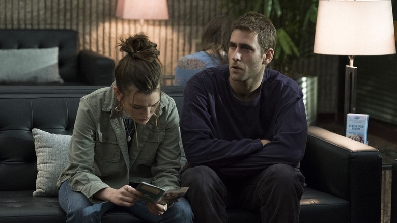 Victoria Pedretti as Eleanor Crain and Oliver Jackson-Cohen as Luke Crain sitting together on a couch in The Haunting of Hill House.