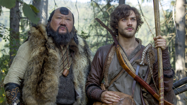 Benedict Wong as Kublai Khan wearing fur next to Lorenzo Richelmy as Marco Polo holding wooden weapon in Marco Polo