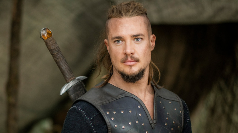 Alexander Dreymon as Uhtred of Bebbanburg with leather vest and sword behind his back in The Last Kingdom