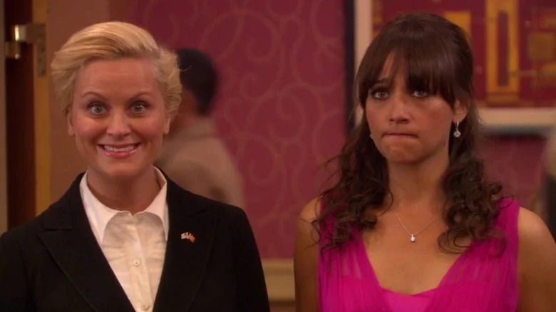 Leslie Knope (Amy Poehler) smiles at the camera as Ann Perkins (Rashida Jones) grimaces in Parks and Recreation