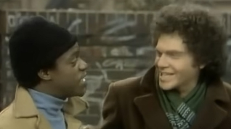 Wilbur Murray wearing a hat outside and talking to Carvelli