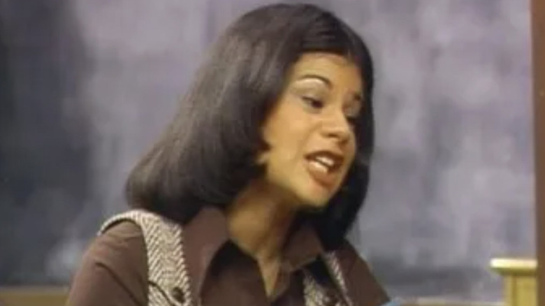 Judy Borden holding books in a classroom and speaking