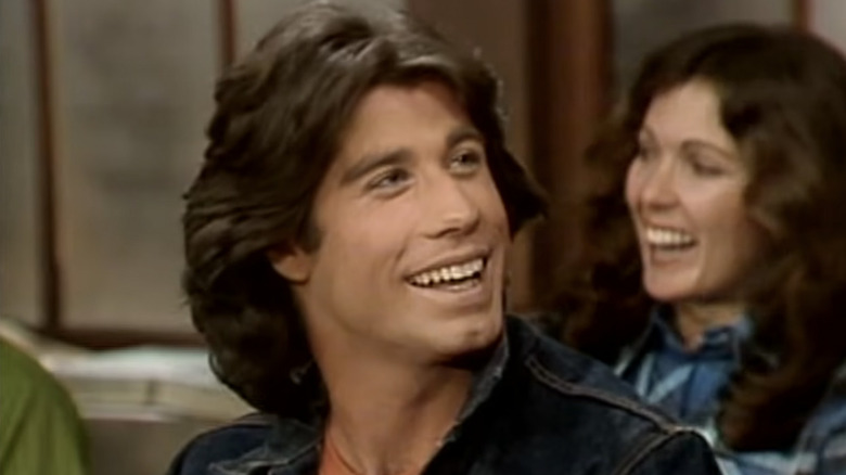 Vinnie Barbarino smiling while sitting in front of a girl in class