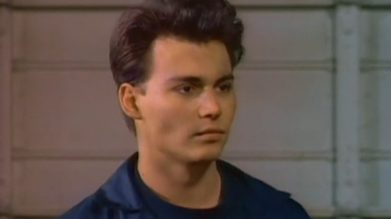 A close-up of Officer Tom Hanson in a blue jacket with an industrial background