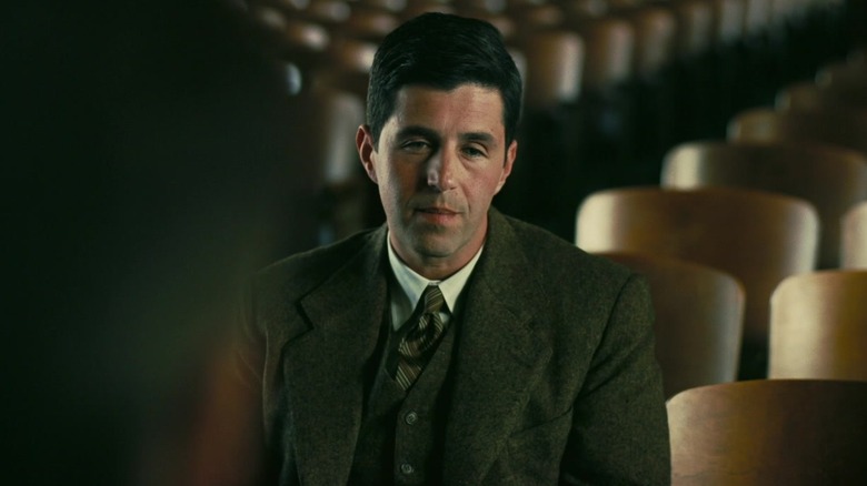 Josh Peck as Kenneth Bainbridge, sitting in an empty auditorium in Oppenheimer