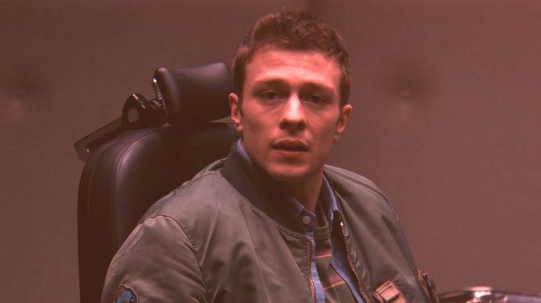 Thomas Shepherd wearing a grey jacket sitting in a black chair in "VisionQuest."