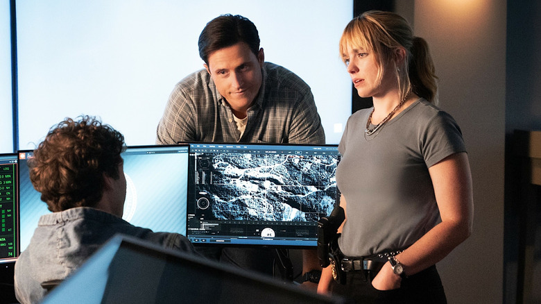 Sean Sullivan sitting at a computer with Wyatt Sellers and Addy Ross standing nearby in NCIS: New York
