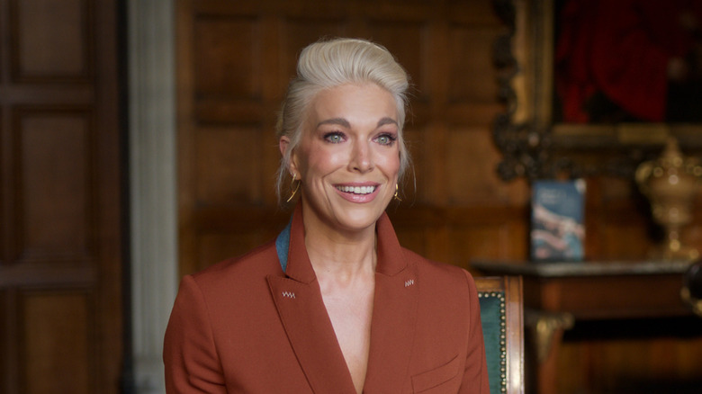 Hannah Waddingham with blond hair tied back wearing a brown coat.