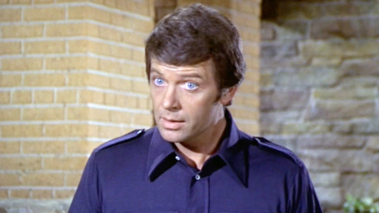 Mike Brady wearing a blue shirt looking stern