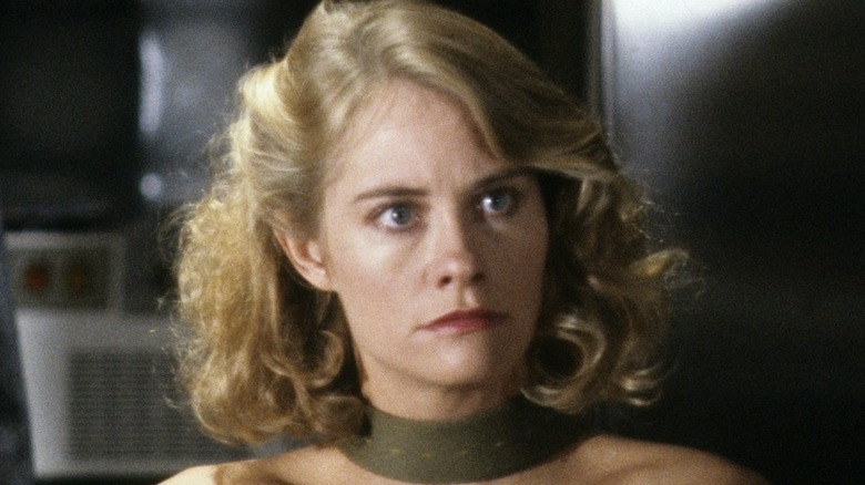 David (Bruce Willis) with an annoyed expression and Maddie (Cybill Shepherd) with wide eyes sit strapped to chairs by their bodies and necks in Moonlighting