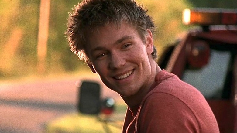 Lucas Scott smiling in front of a red truck in One Tree Hill (2003)