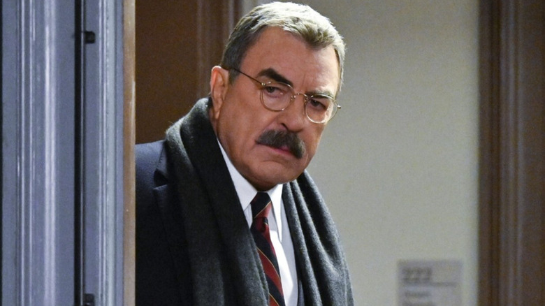 Frank Reagan (Tom Selleck) peers around a corner on Blue Bloods.
