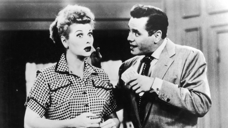 Ricky holds a stack of money as Lucy's looks stunned