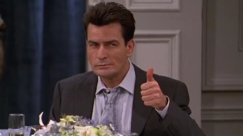 O vice-prefeito de Nova York, Charlie Crawford, de terno, sentado à mesa fazendo sinal de positivo com o polegar 