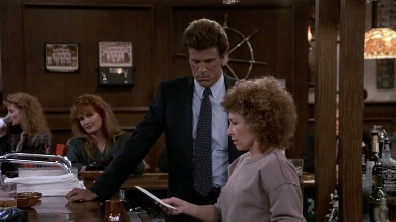 Carla reading note from Eddie while standing with Sam behind bar at Cheers