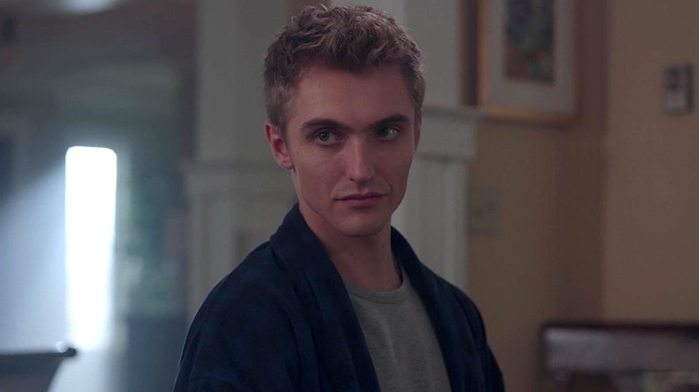 Gri gömlekli ve mavi ceketli şık Riverdale'deki bir evde duruyor