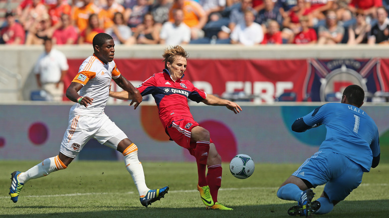 Chicago Fire'dan 17 numaralı Chris Rolfe, 1 Eylül 2013'te Bridgeview, Illinois'de Toyota Park'ta oynanan MLS maçında Kofi Sarkodie #8'i savunurken Houston Dynamo'nun 1 numaralı Tally Hall'una karşı şut atıyor.