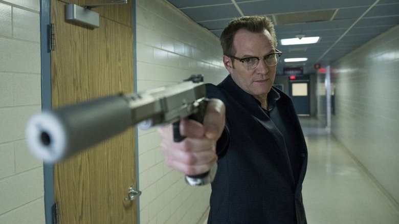 Noah Bennet pointing a silver silenced pistol at someone in a corridor