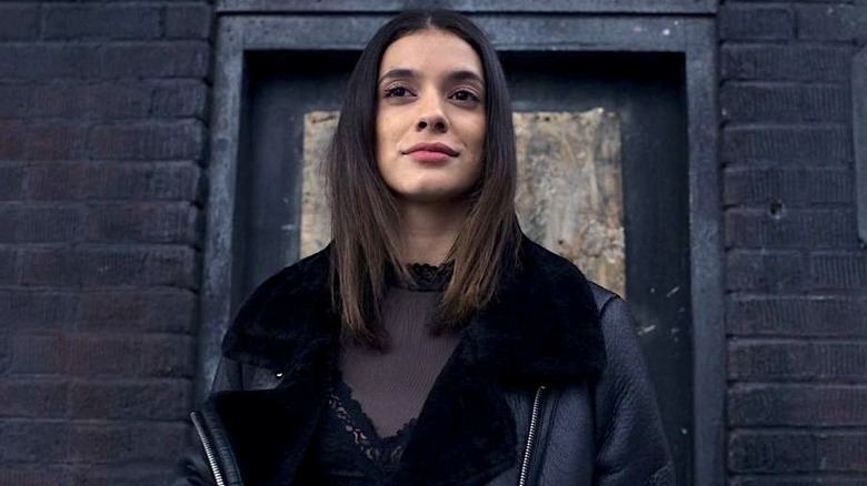Dodge wearing all black in front of a black door in "Locke & Key"