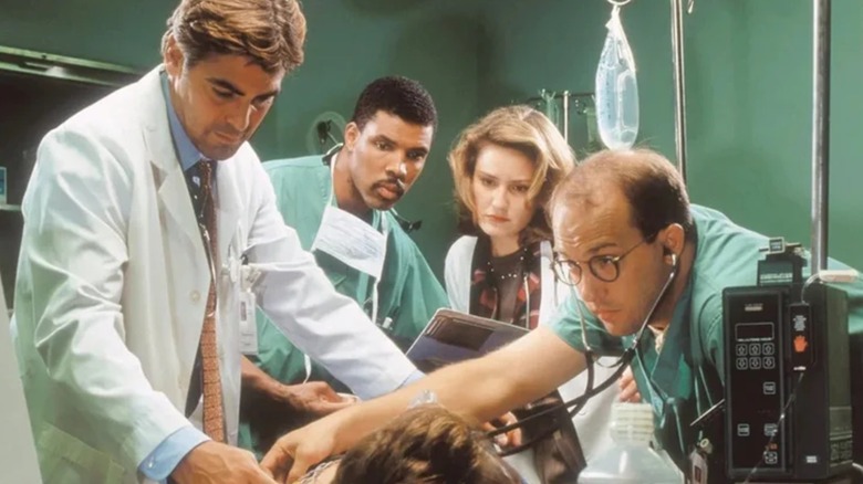 Eriq La Salle as Dr. Peter Benton, Maura Tierney as Dr. Abott, George Clooney as Dr. Ross, and Anthony Edwards as Dr. Greene as Dr. Abby Lockhart in the operating room on ER