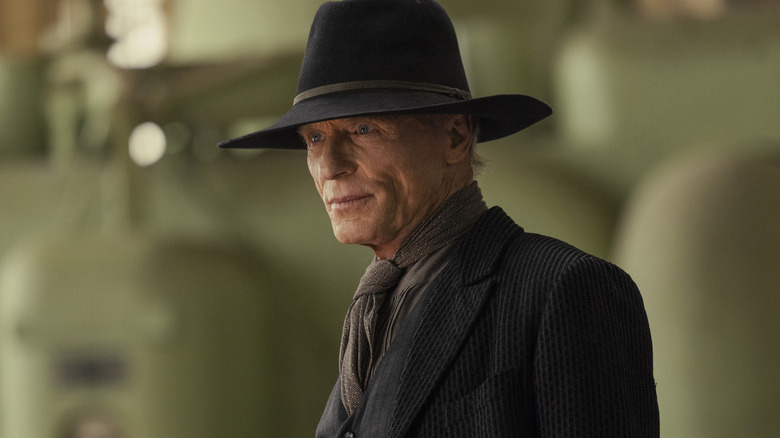 Siyah takım elbiseli ve kovboy şapkalı Adam Westworld'de yeşil makinelerin önünde duruyor