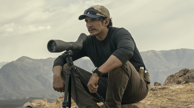 Gabriel Luna as Freddy Strain sitting on rocks behind sniper telescope