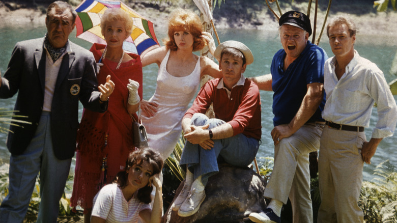 The Gilligan's Island castaways pose for a still photo:  Jim Backus as Mr. Howell, Natalie Schafer as Mrs. Howell, Dawn Wells as Mary Ann, Tina Louise as Ginger, Bob Denver as Gilligan, Alan Hale, Jr. as The Skipper, and Russell Johnson as The Professor.