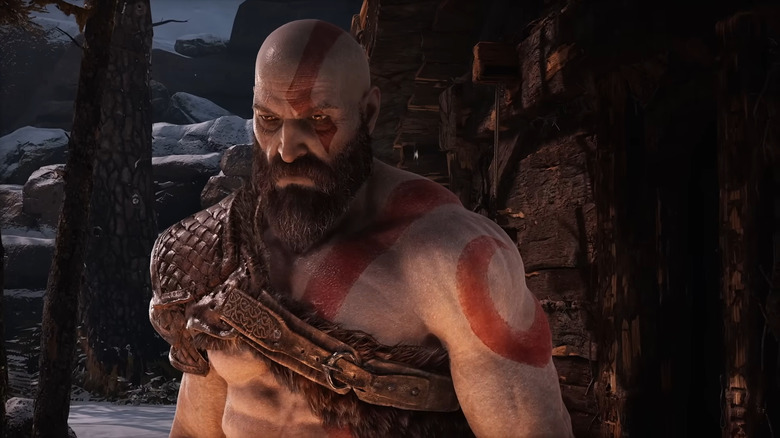 Kratos lit by fire in a snowy forest in "God of War" (2018)