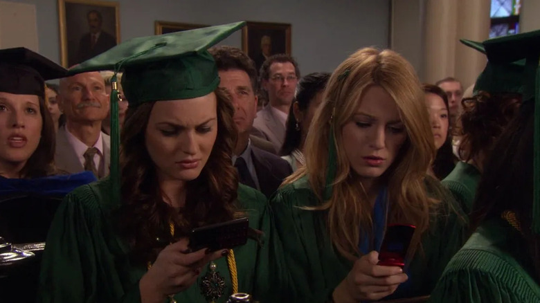 Blair and Serena reading a Gossip Girl blast during their high school graduation on Gossip Girl
