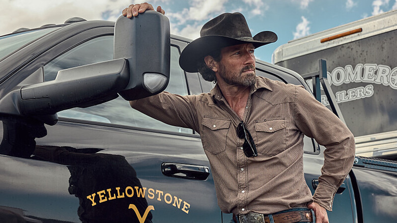 Ian Bohen as Ryan in Yellowstone, leaning against side mirror of pickup truck