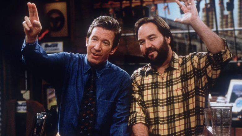 Tim Allen as Tim Taylor and Richard Karn as Al Borland waving on an episode of Home Improvement