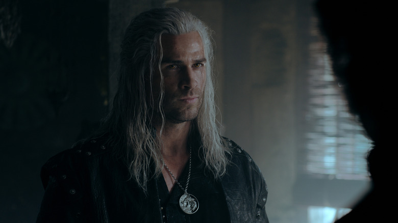 Geralt (Liam Hemsworth) in a dark room talking to someone on The Witcher