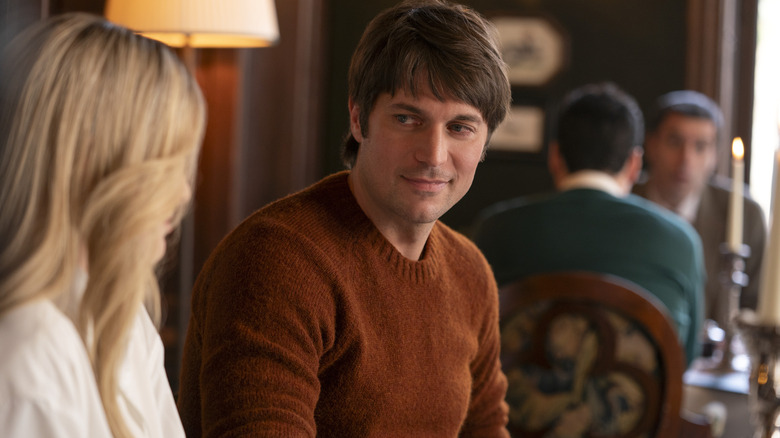 Lucas de suéter marrom conversando com Camille sobre Emily em Paris