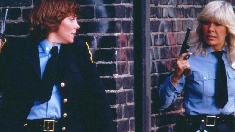 Christine Cagney and Mary Beth Lacy holding pistols in front of a wall