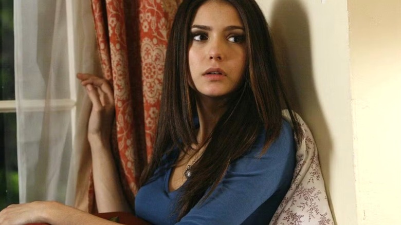 Elena (Nina Dobrev) leaning against a curtain on "The Vampire Diaries"