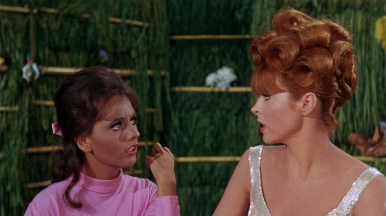 Mary Ann and Ginger sitting at table in hut talking