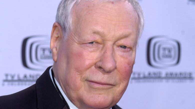 Russell Johnson in black suit, smiling slightly