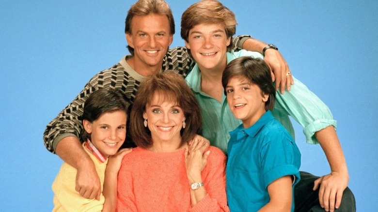 The cast of The Hogan Family smiling against a blue background, featuring Josh Taylor as Michael, Jason Bateman as David, Danny Ponce as Willie, Valerie Harper as Valerie, and Jeremy Licht as Mark.