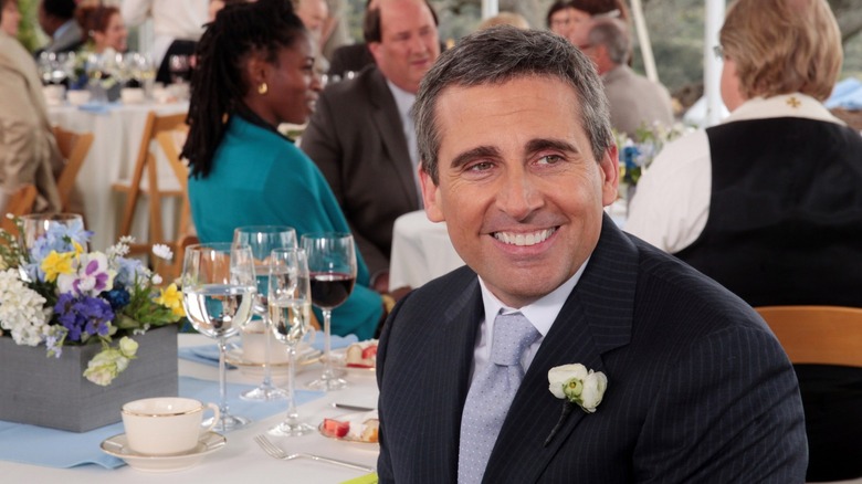 Michael Scott sitting at table at Dwight and Angela's wedding in "The Office"