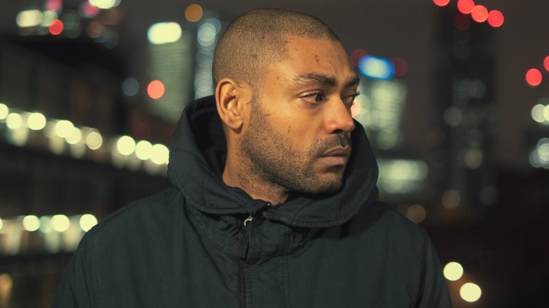 Sully stood against a city skyline at night in Top Boy