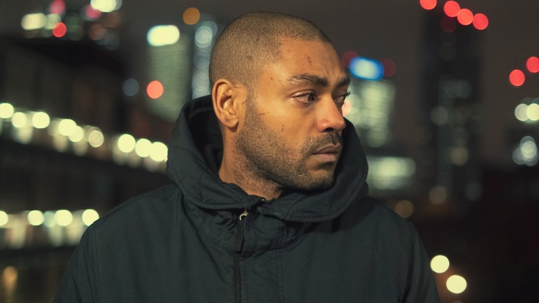 Sully stood against a city skyline at night in Top Boy