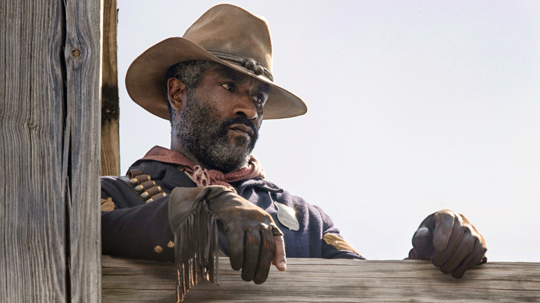 LaMonica Garrett as Thomas in "1883" leaning against a wooden fence