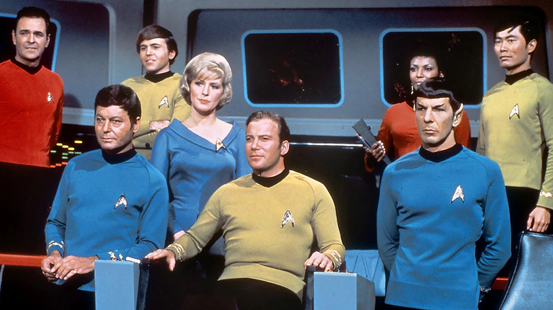 Captain Kirk sits aboard the Enterprise, surrounded by the rest of the ship's crew, on the original series of Star Trek.