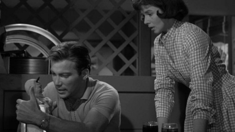 Don Carter stares at the fortune telling machine while sitting in a booth at a diner and his wife Pat Carter looks on while standing next to the table