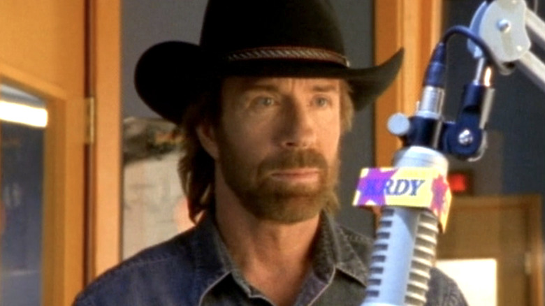 Cordell Walker wearing a cowboy hat standing in front of a microphone in Walker, Texas Ranger