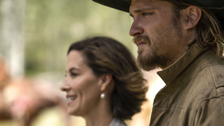 Kayce Dutton (Luke Grimes) stands uneasily next to a smiling Lynelle Perry (Wendy Moniz) in Yellowstone
