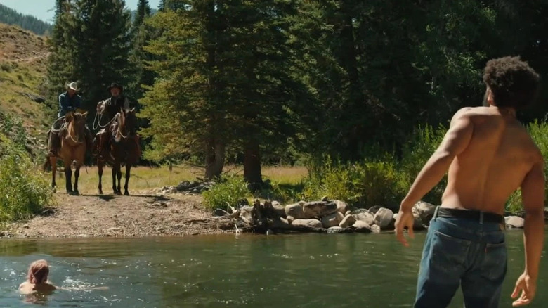 Colby Mayfield (Denim Richards) stands shirtless by a creek facing two horsemen in Yellowstone
